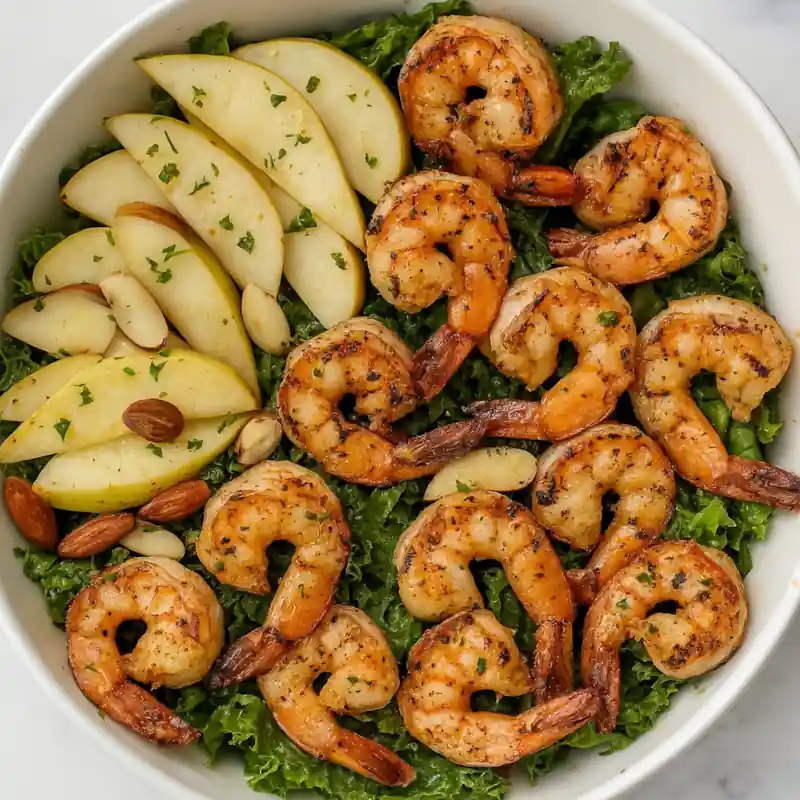 Apple Almond Shrimp Salad with sliced apples, almonds, and kale in a white bowl